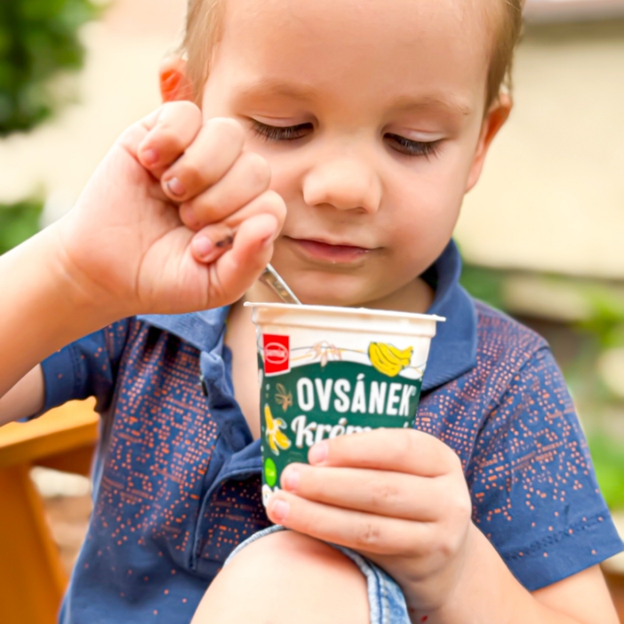 Chlapec jí na lavičce jogurt ovsánek lžičkou